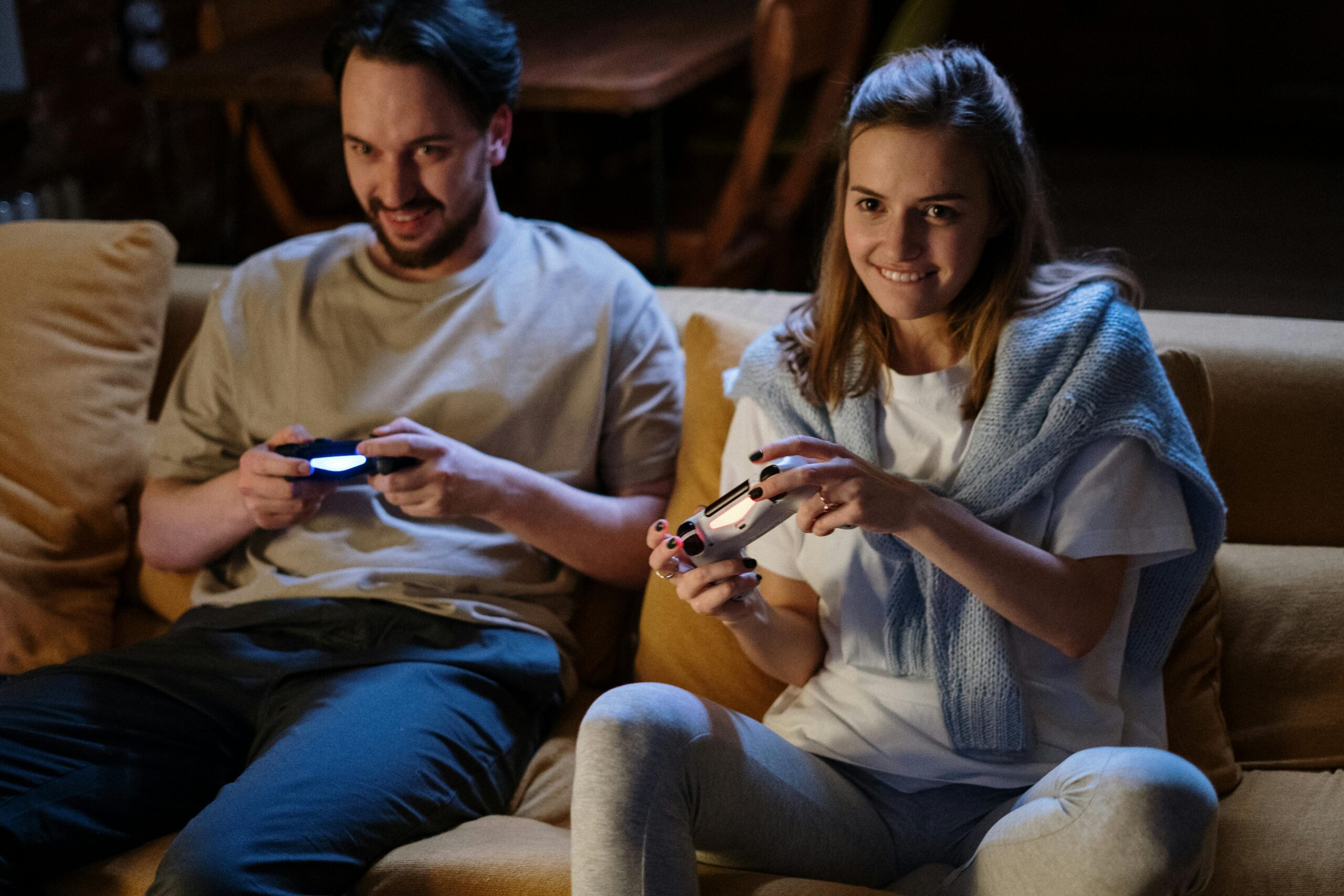 Two people on a couch holding playstation controllers having fun